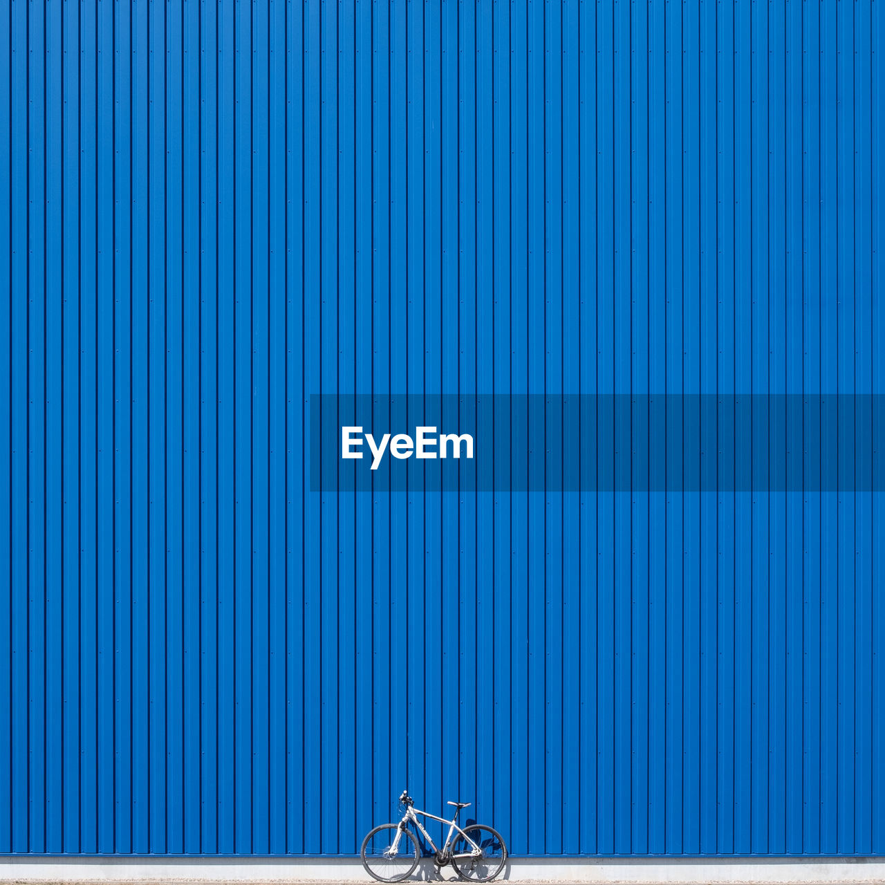 Bicycle parked against blue corrugated iron
