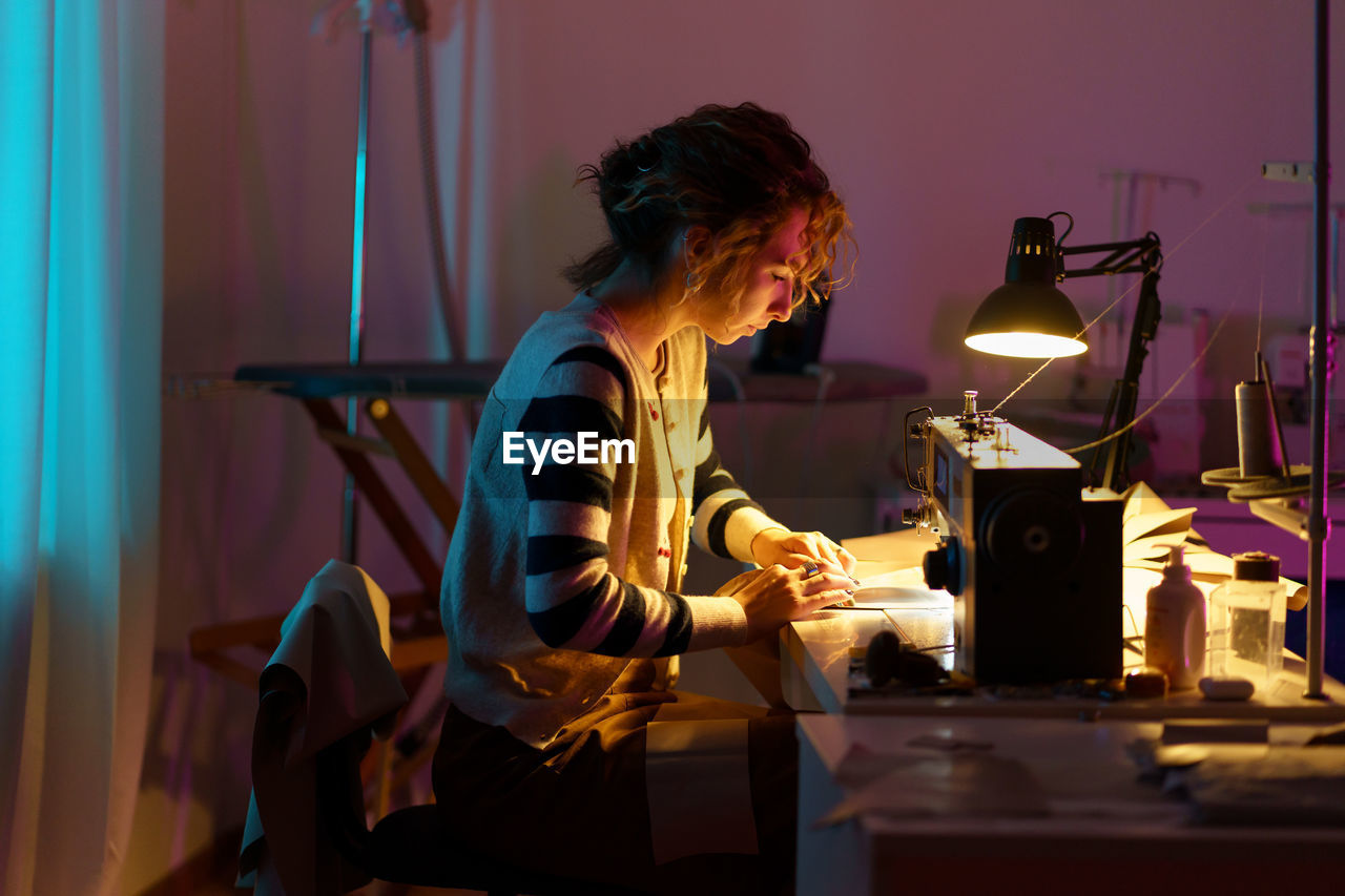 Fashion designer in atelier. young girl seamstress use sewing machine to create bespoke clothes