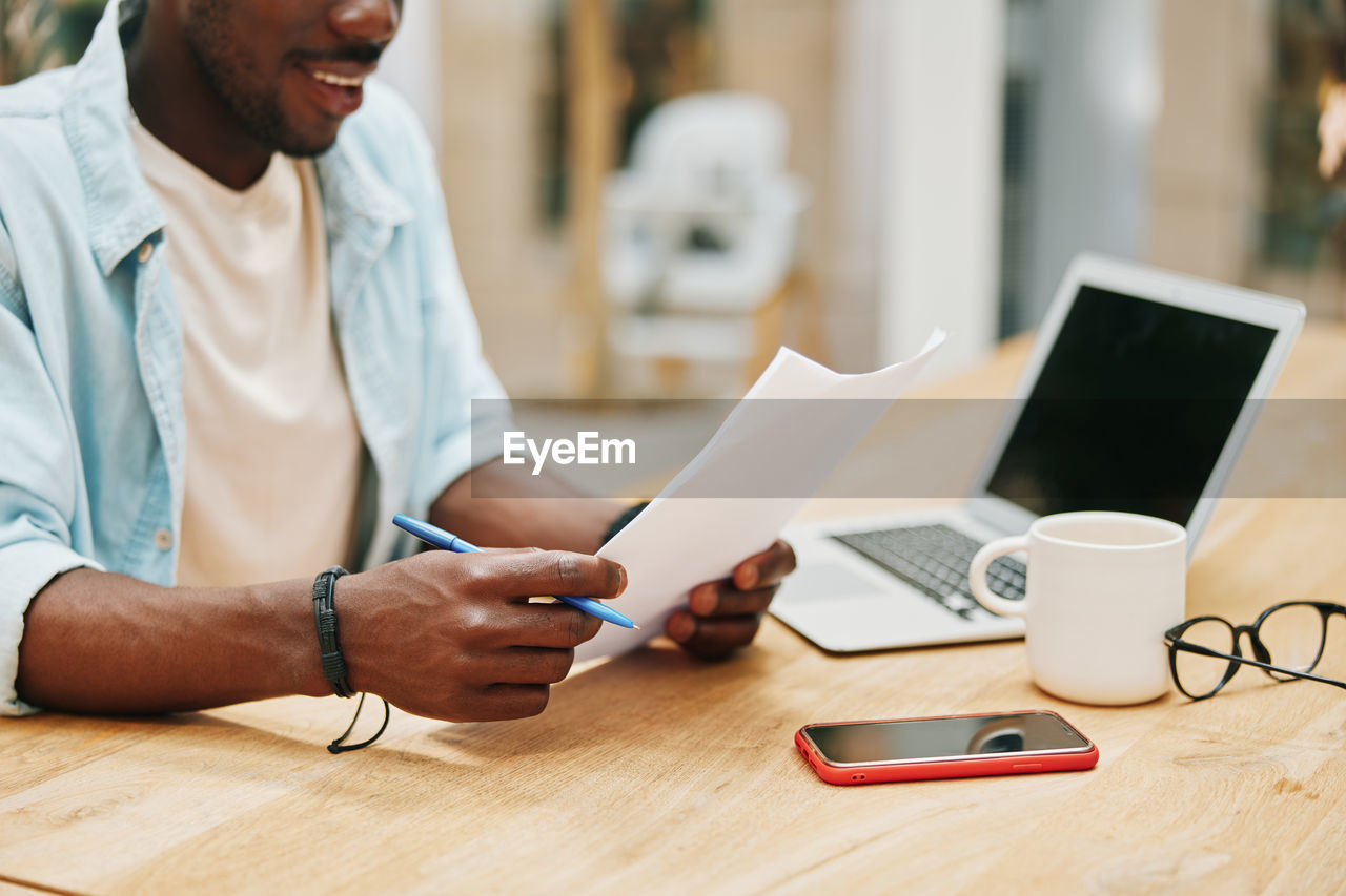 midsection of man using digital tablet at table