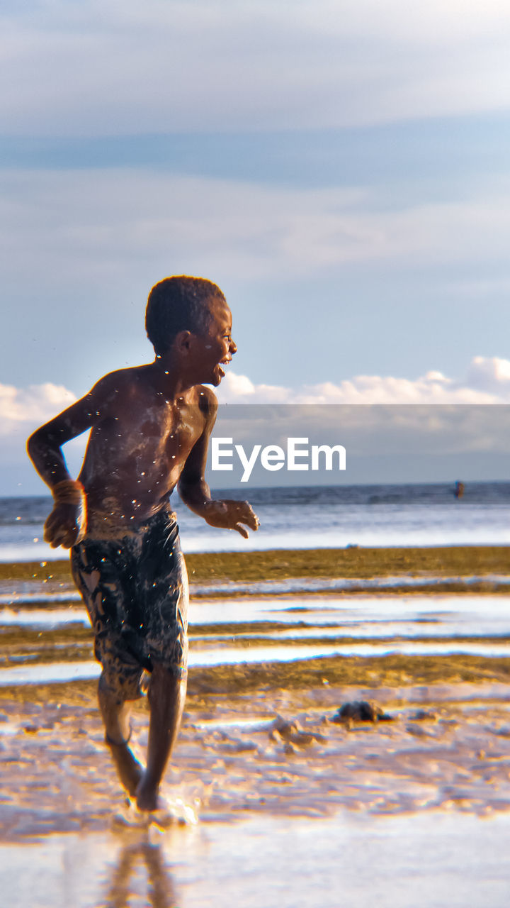 Full length of shirtless boy on beach