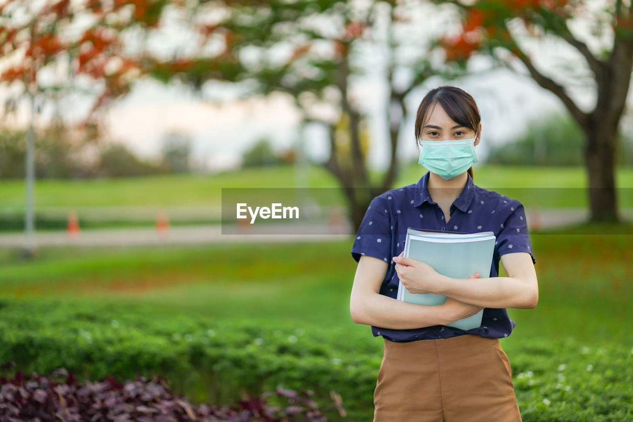 PORTRAIT OF WOMAN STANDING ON FIELD