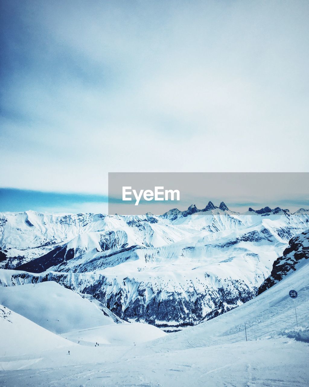 Scenic view of snow covered mountains against cloudy sky