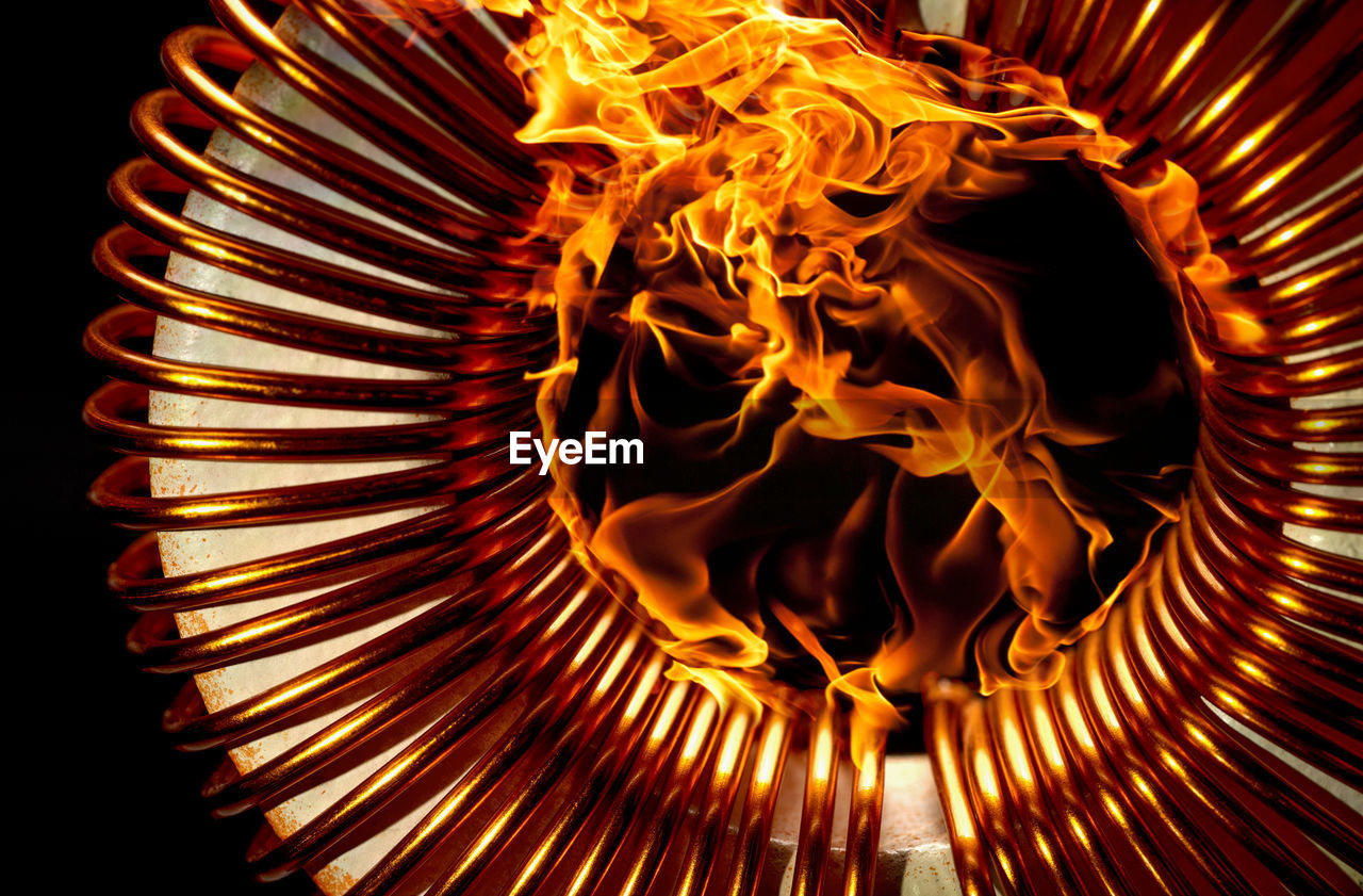 CLOSE-UP OF ILLUMINATED BURNING CANDLES ON METAL