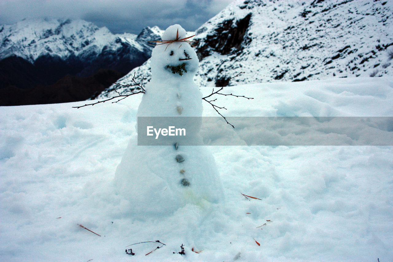 Cute snowman on top of a white snowy mountain with winter landscape