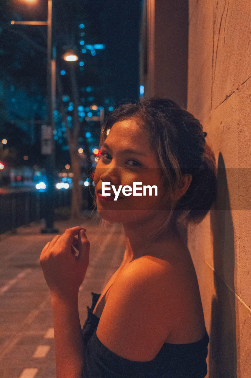 PORTRAIT OF YOUNG WOMAN SMOKING WHILE LOOKING AWAY