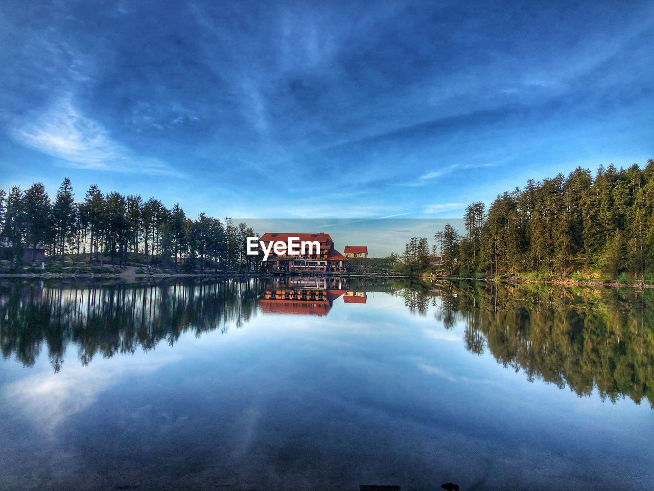 Reflection of trees and buildings in lake against sky