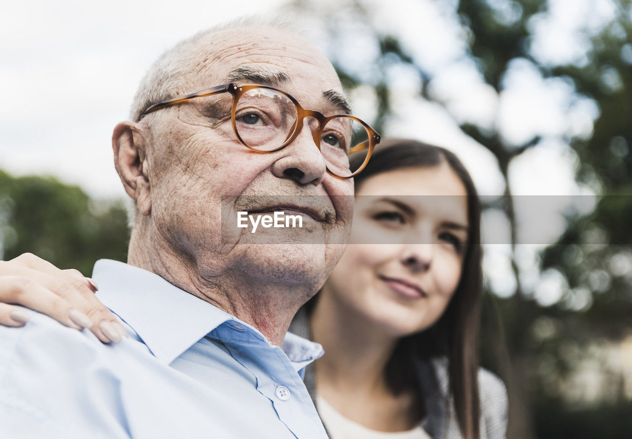 Portrait of self-confident senior man with granddaughter in the background