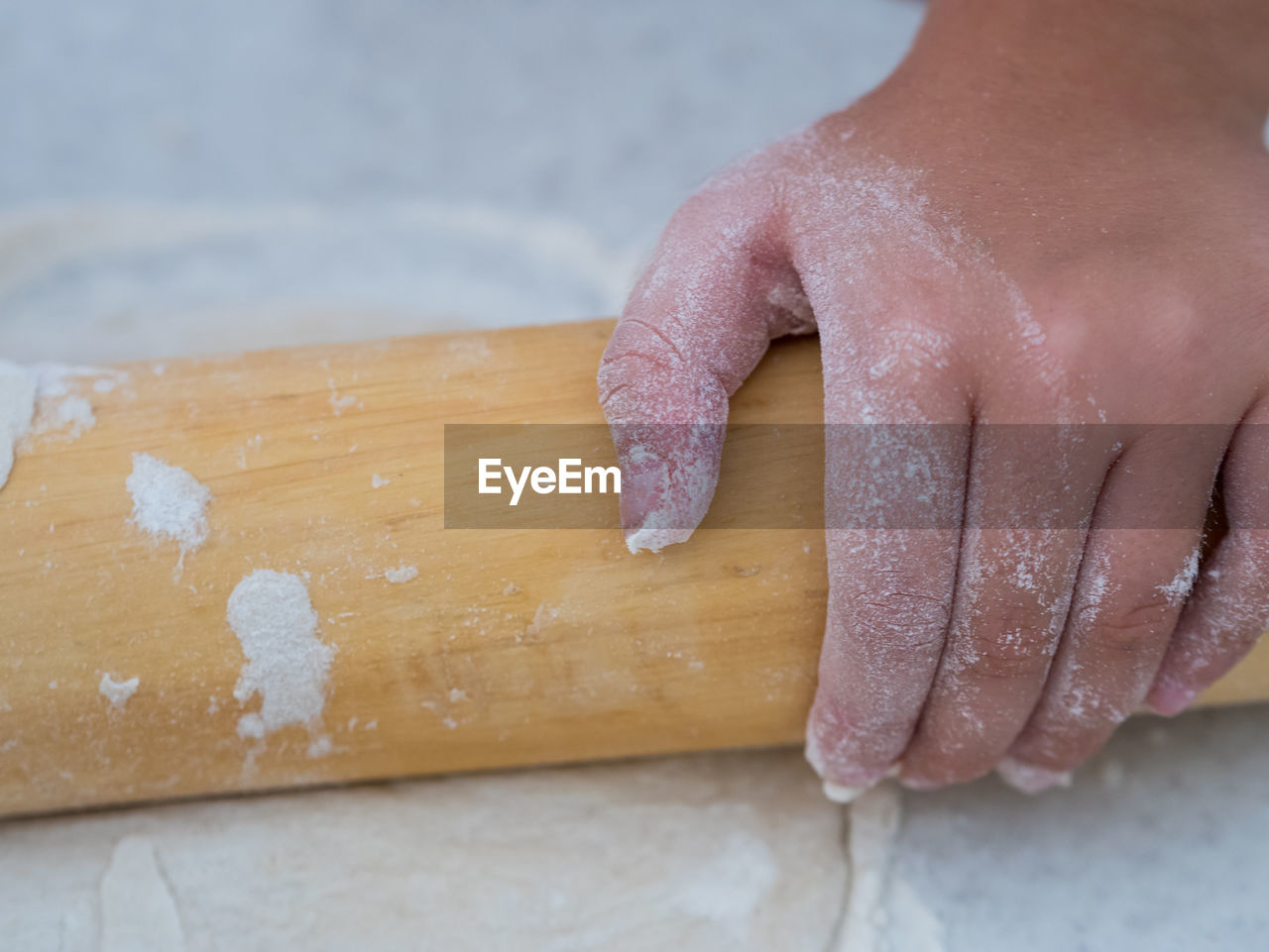 Cropped hand of girl rolling dough