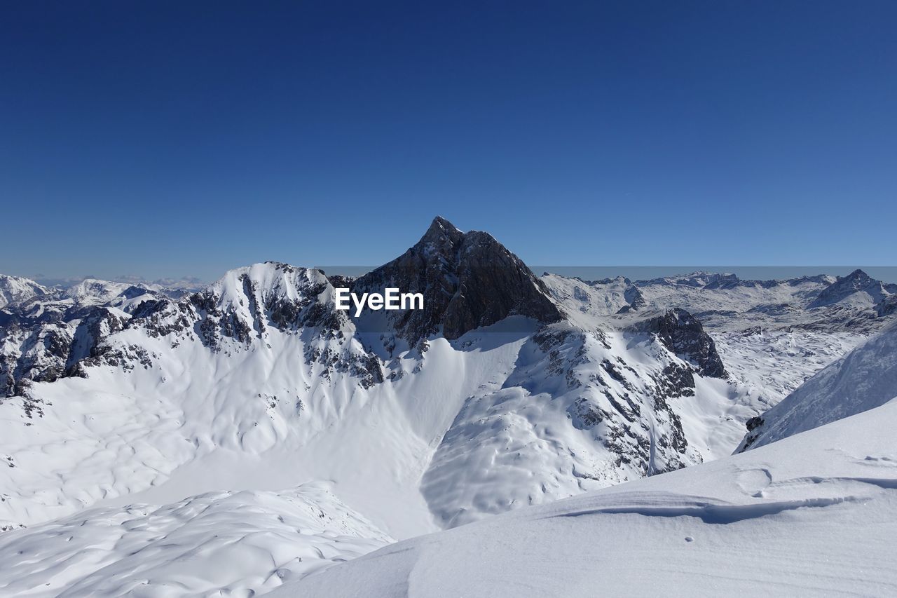 Scenic view of snowcapped mountains against clear blue sky