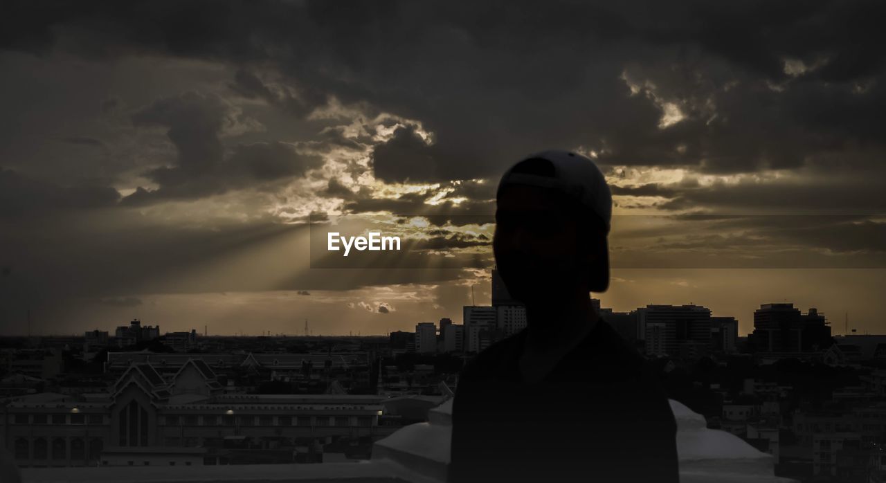 PORTRAIT OF SILHOUETTE MAN LOOKING AT CITY BUILDINGS