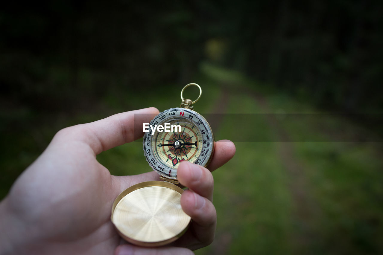 Cropped hand holding compass in forest