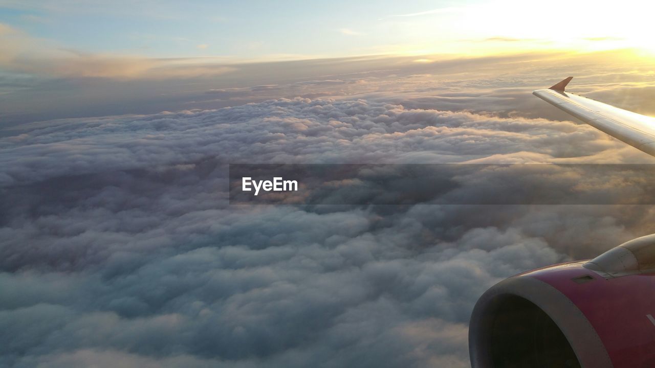 Cropped image of airplane wing above cloudy sky