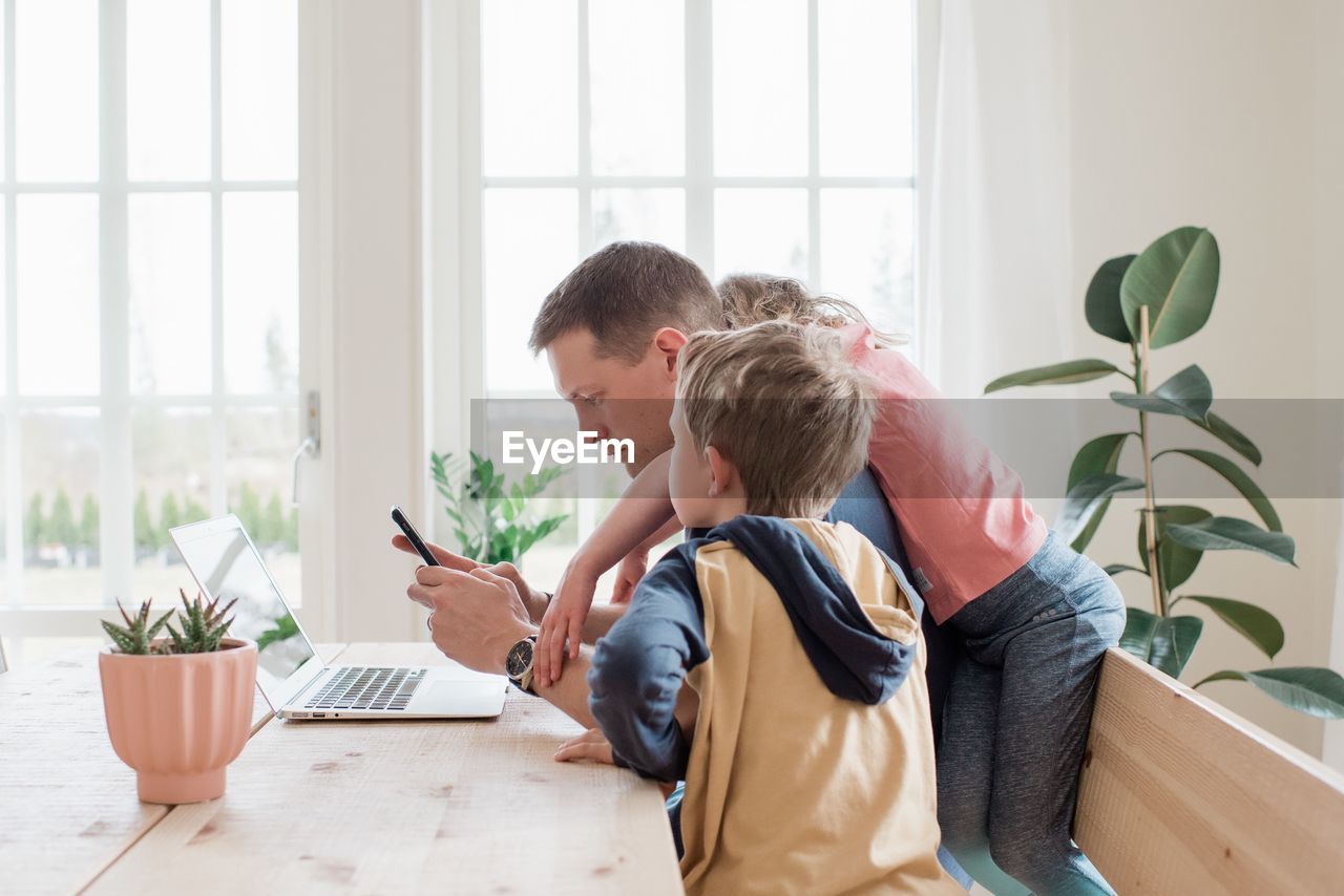 Father working from home with his kids climbing over him