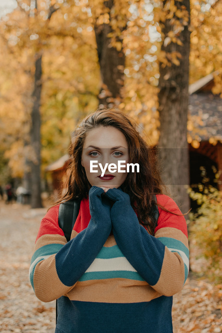 Portrait of beautiful young woman standing in park during autumn