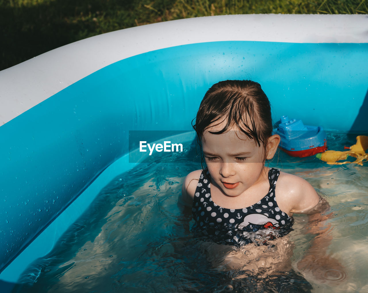 Portrait of a happy child in the pool. cheerful little girl plays toys in the water. 