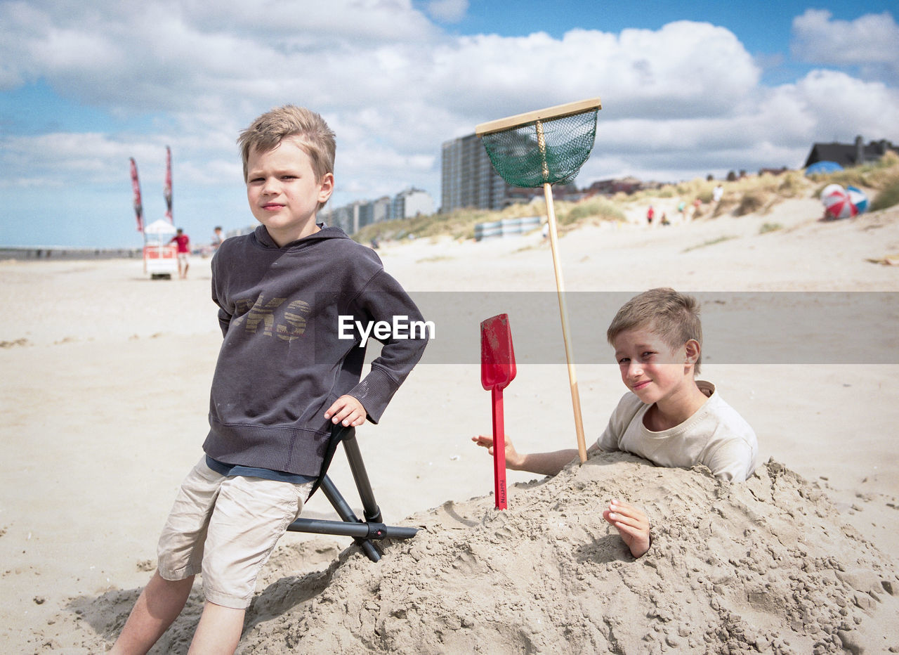 Portrait of happy boy playing on beach against sky