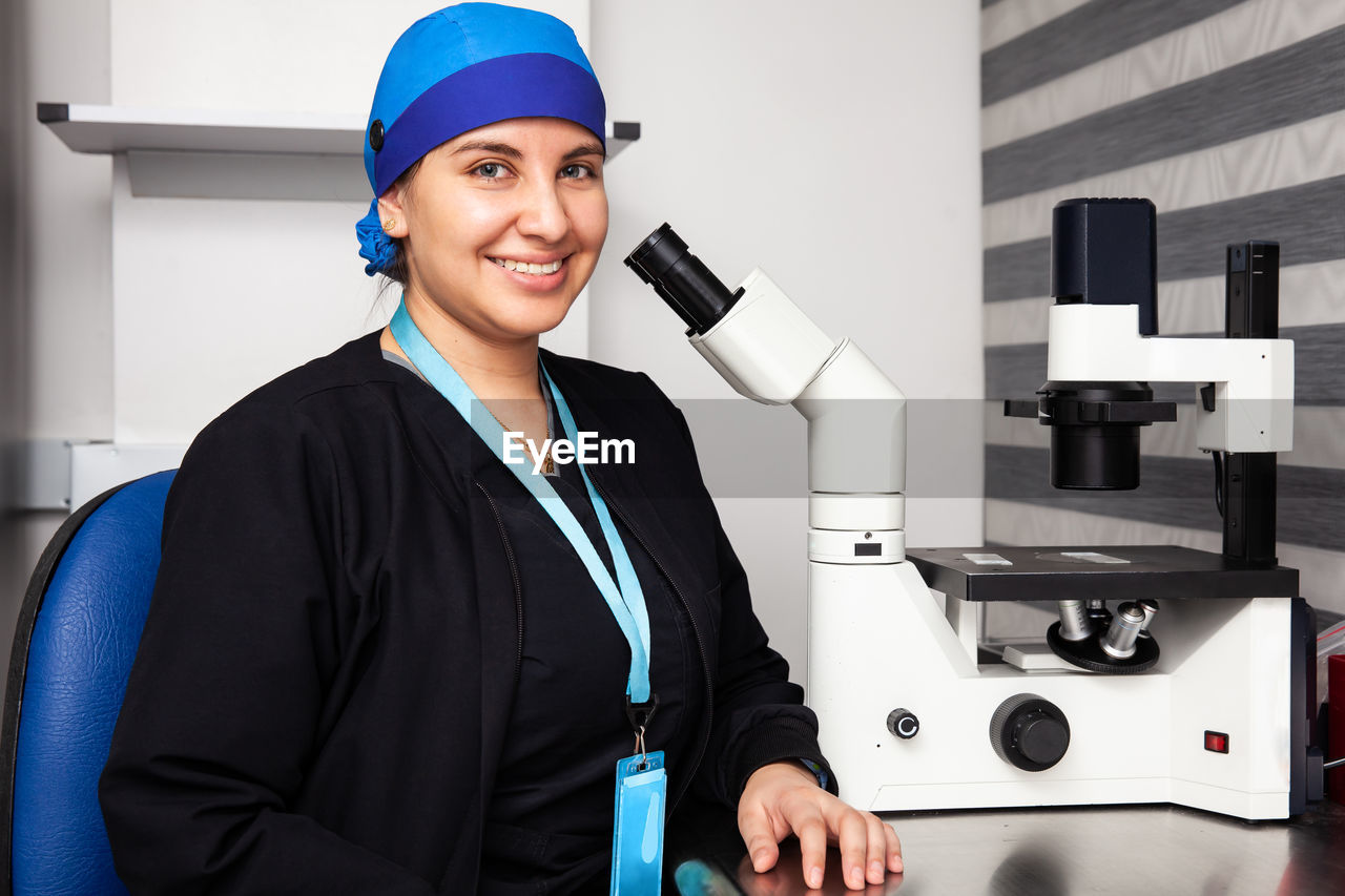 Beautiful young female scientist in the laboratory next to an inverted microscope
