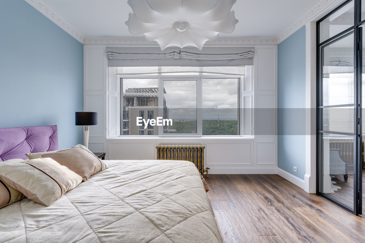 Large bright room with blue walls and a huge white chandelier and glass wall