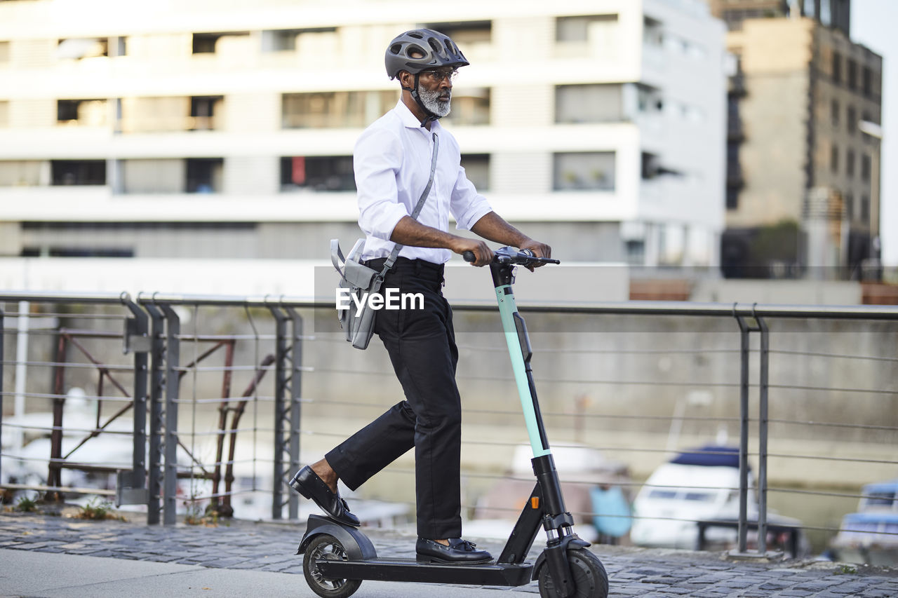 Mature businessman riding e-scooter