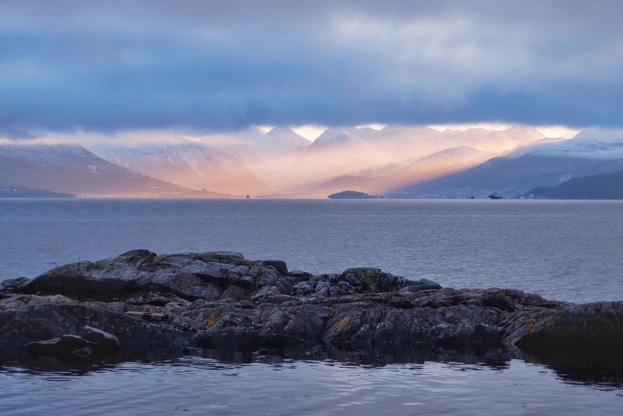 ROCKS BY SEA AGAINST SKY