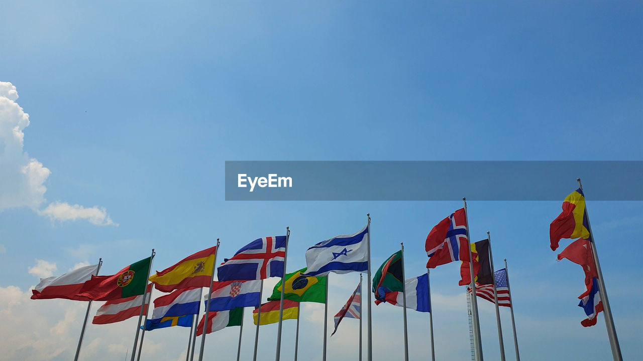 LOW ANGLE VIEW OF FLAGS AGAINST BLUE SKY