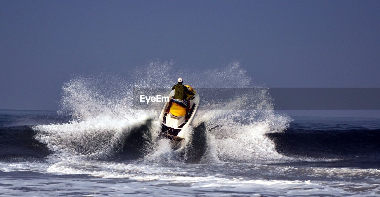 Rear view of man riding jet boat on sea against sky