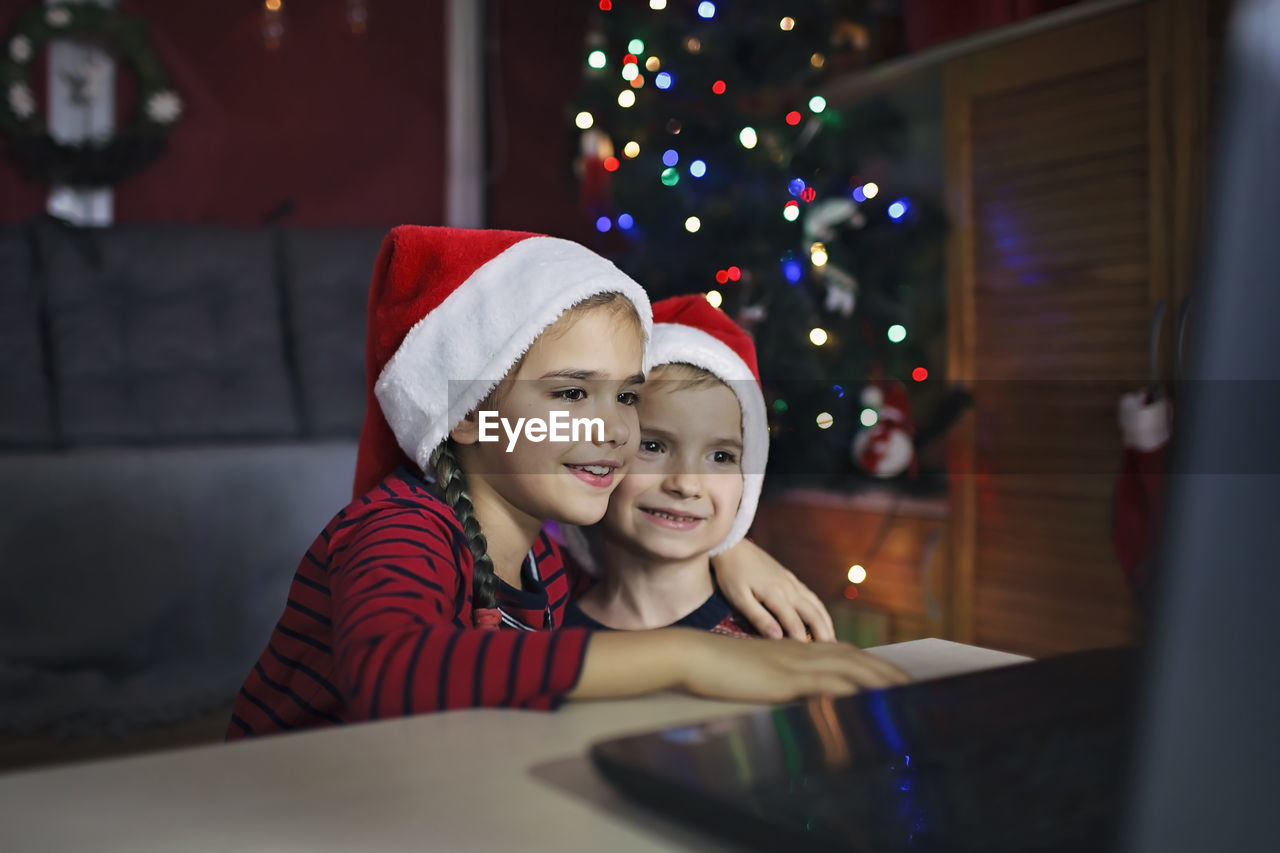 Safe online christmas. happy family in santa red hats celebrating virtually via internet