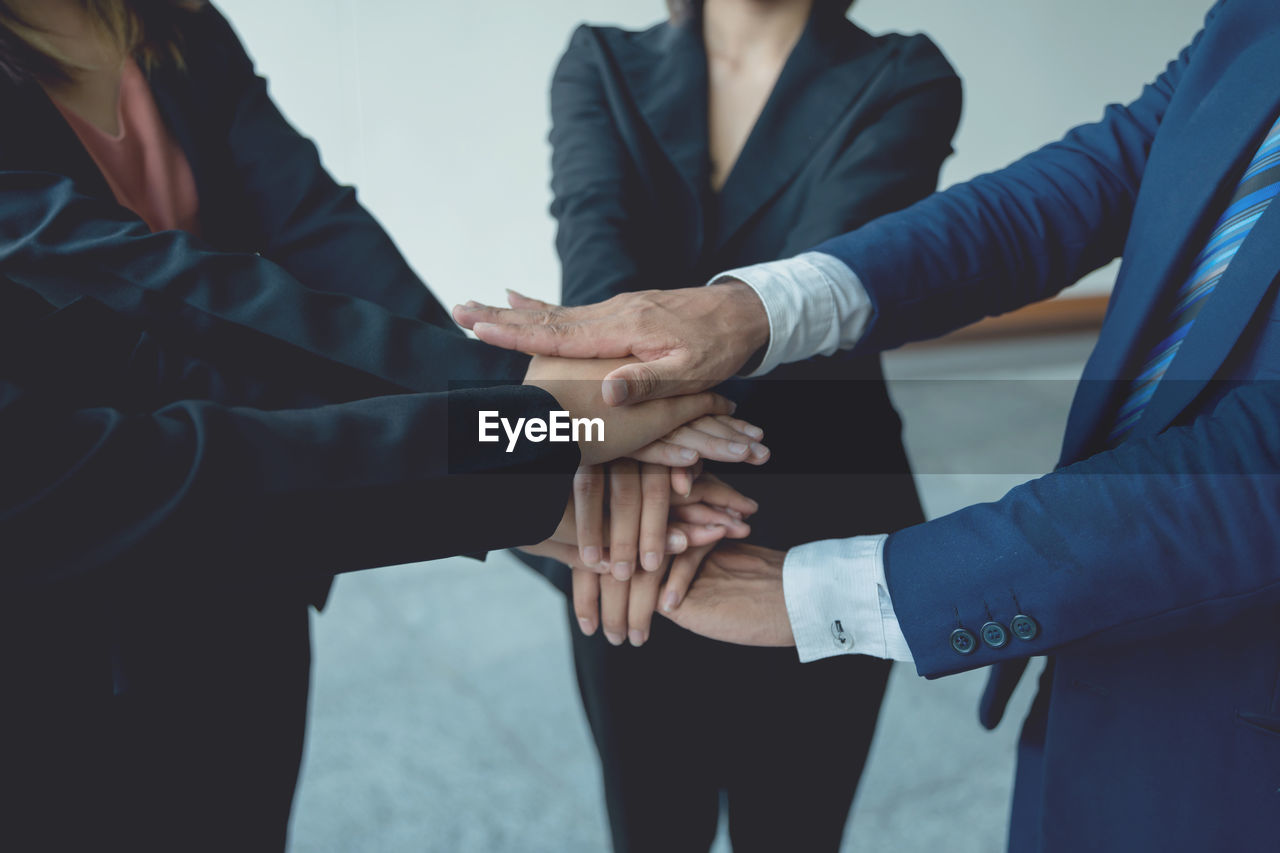 midsection of businessmen stacking hands