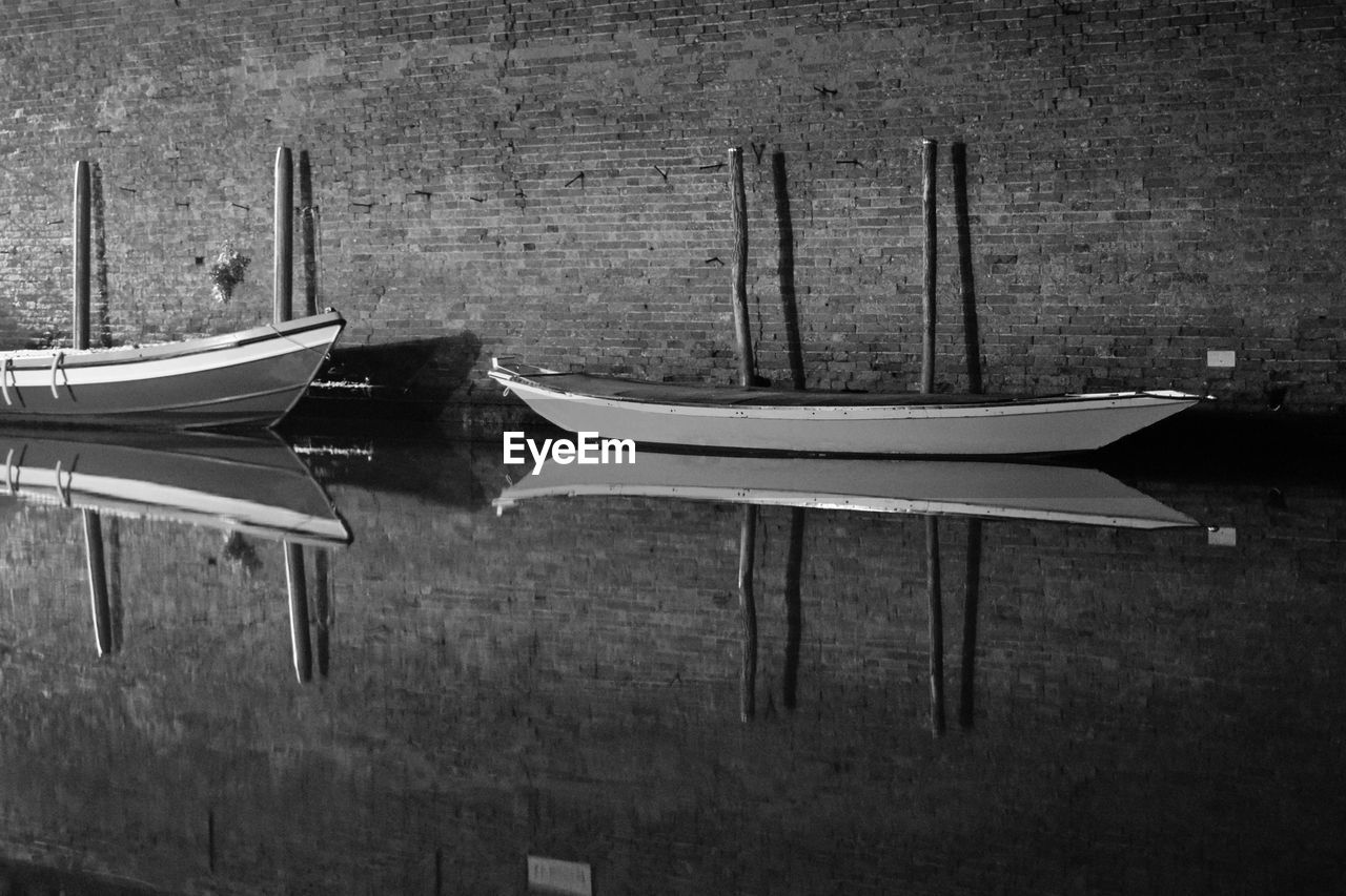 Boats moored on lake by wall