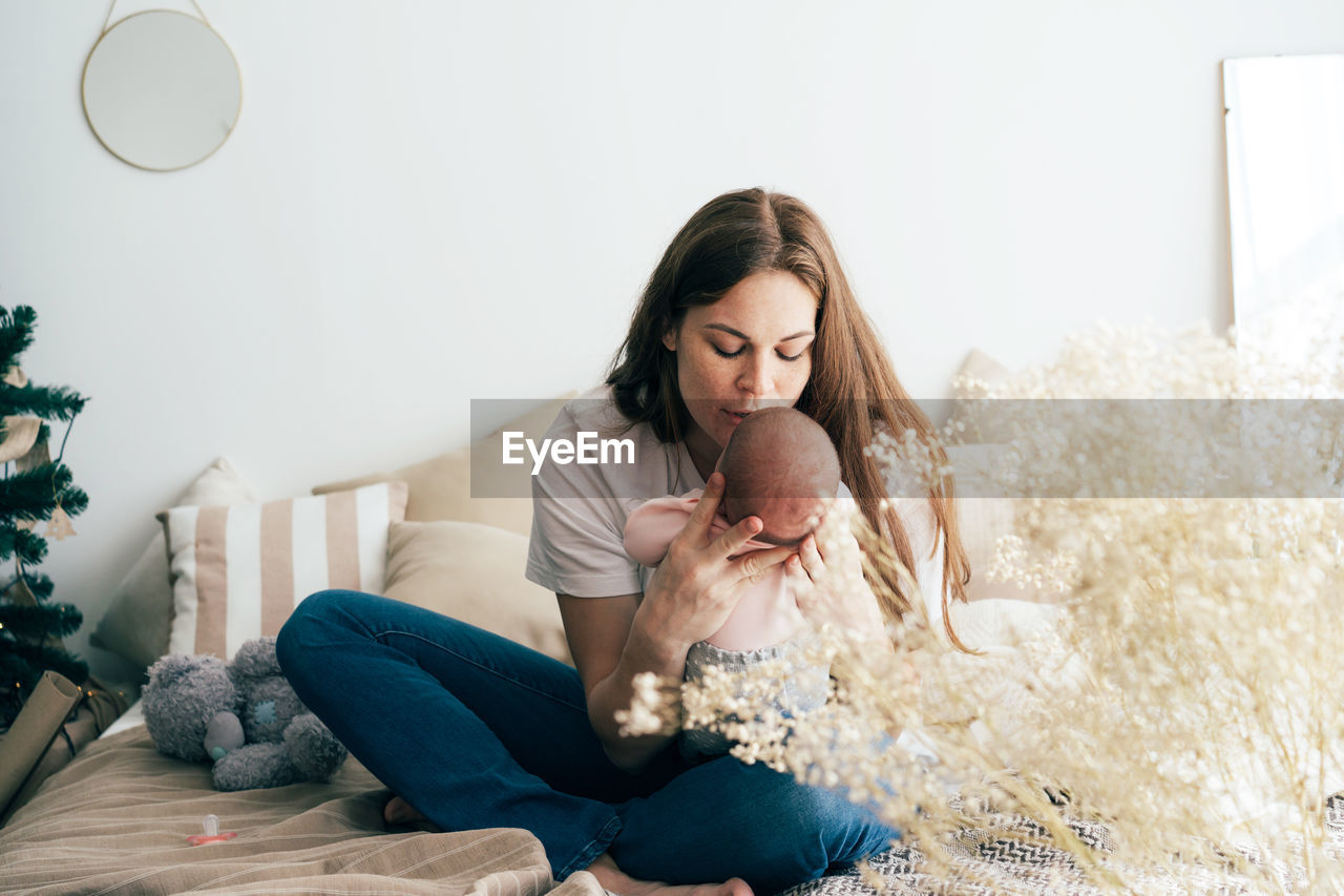 Full length of mother embracing baby at home