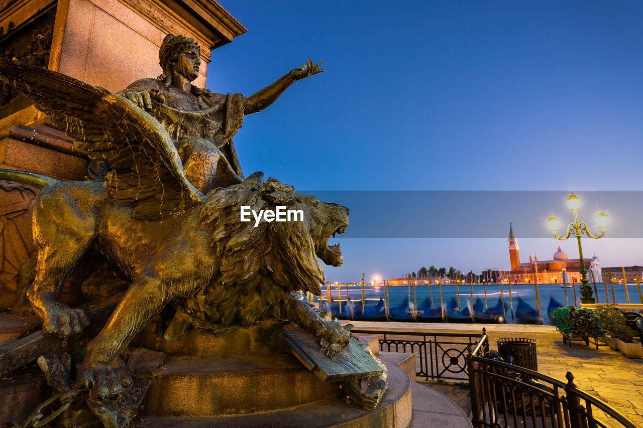 STATUE OF ILLUMINATED BUILDING AGAINST SKY