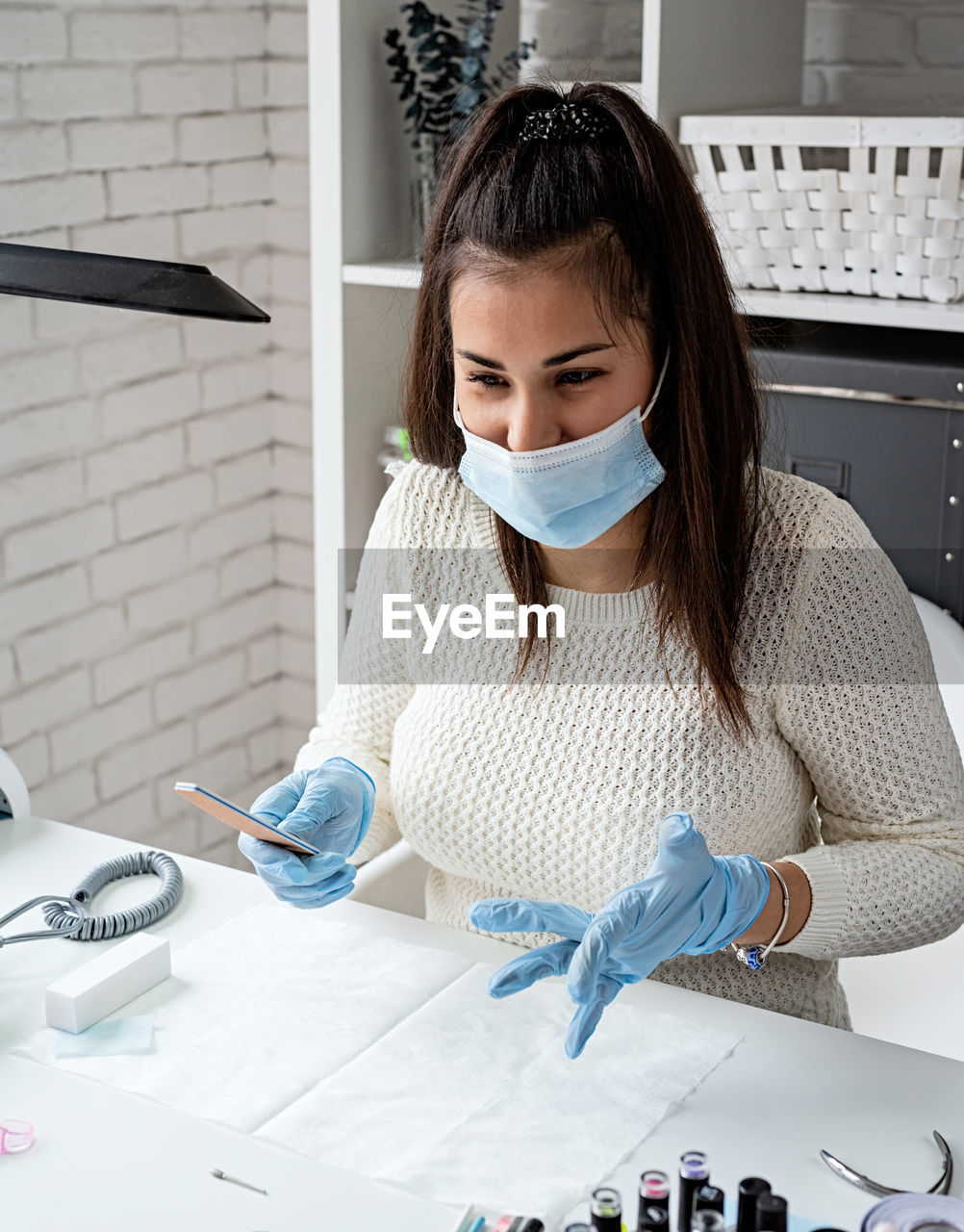 Young woman wearing glove and mask working at salon