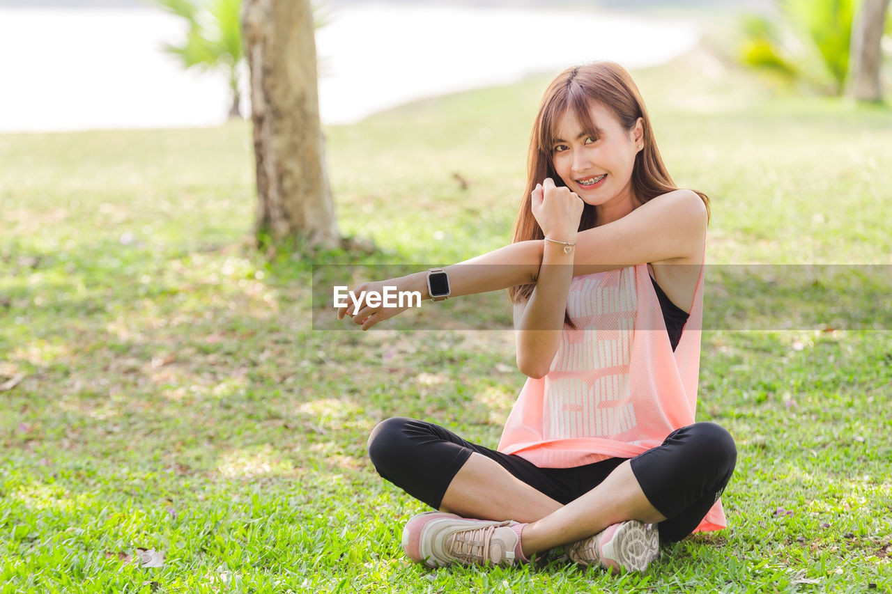 Portrait of woman exercising while sitting on grass