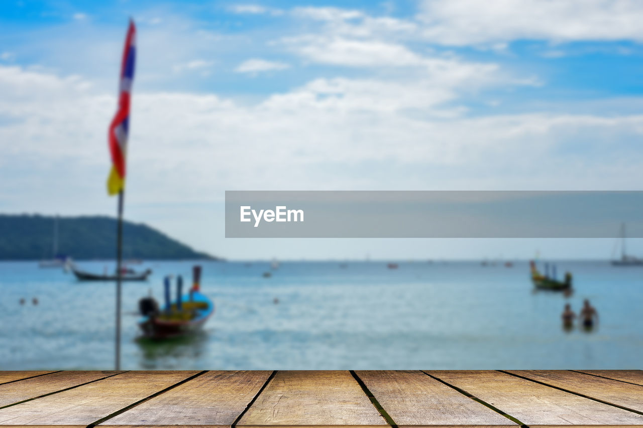 water, sky, sea, cloud, nature, flag, day, nautical vessel, ocean, shore, wood, tranquility, beach, scenics - nature, beauty in nature, tranquil scene, transportation, vehicle, vacation, coast, no people, outdoors, pier, patriotism, mode of transportation, land, ship, boat, bay, blue, travel, horizon, focus on foreground, travel destinations