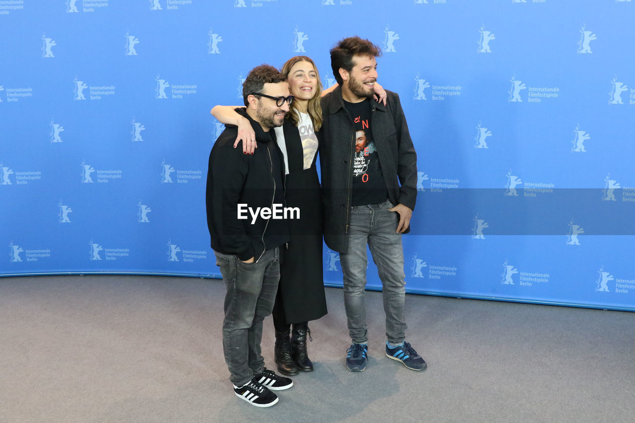 YOUNG FRIENDS STANDING AGAINST BLUE WALL