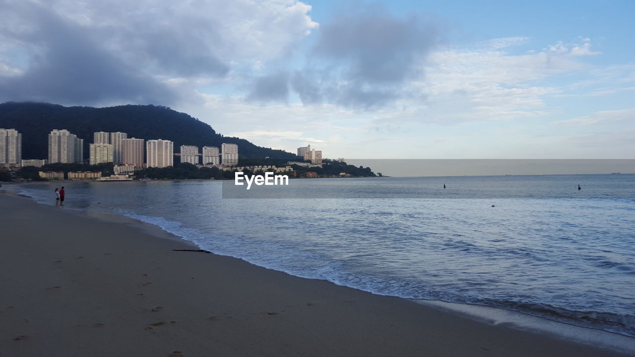 Scenic view of sea by buildings against sky