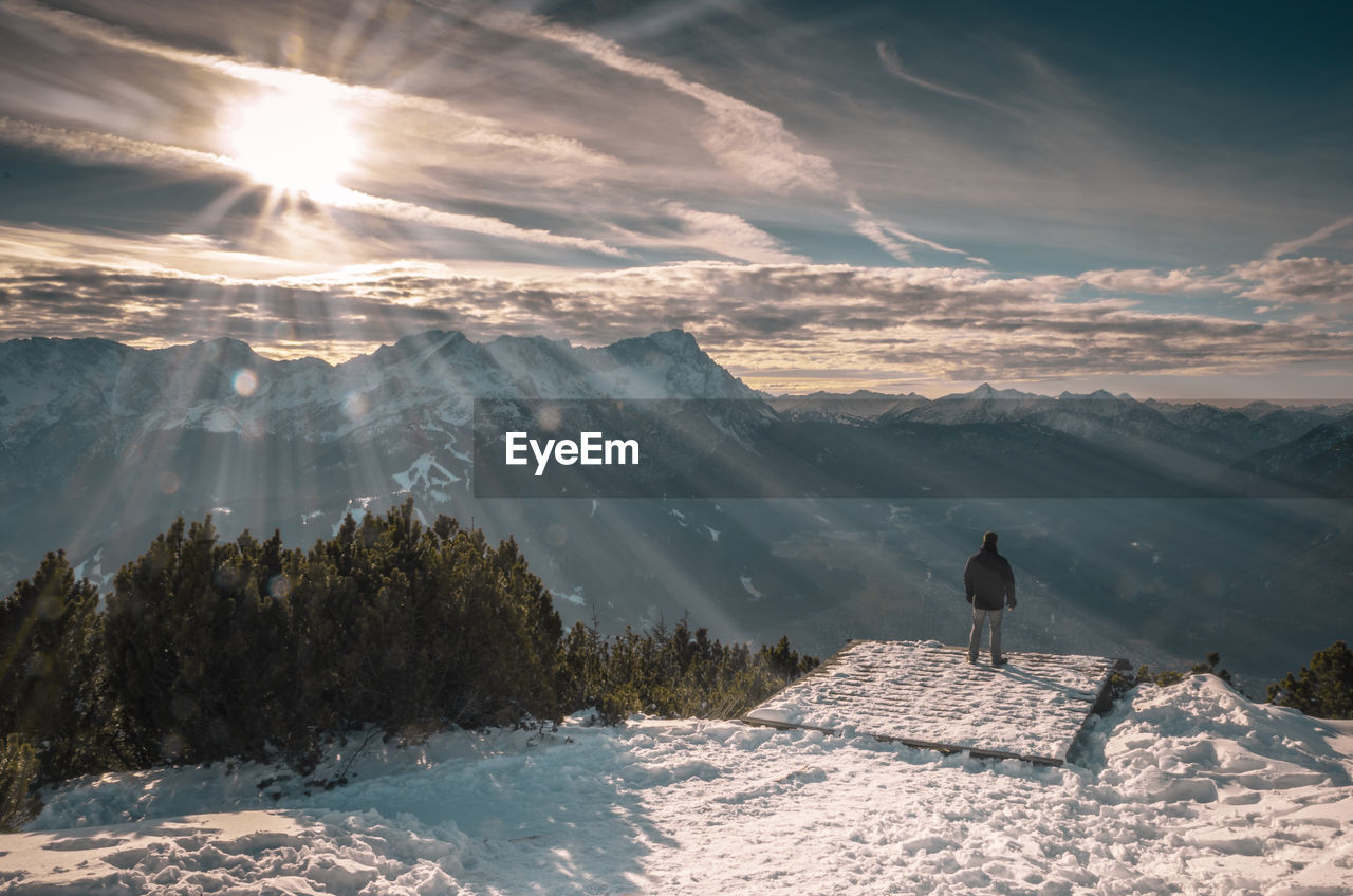 Man standing at observation point against snowcapped mountains