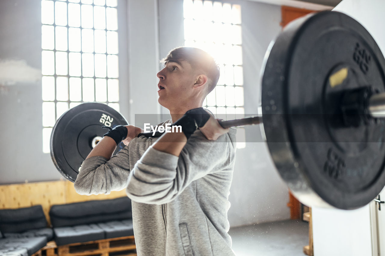 Young man lifting dumbbell exercising in gym