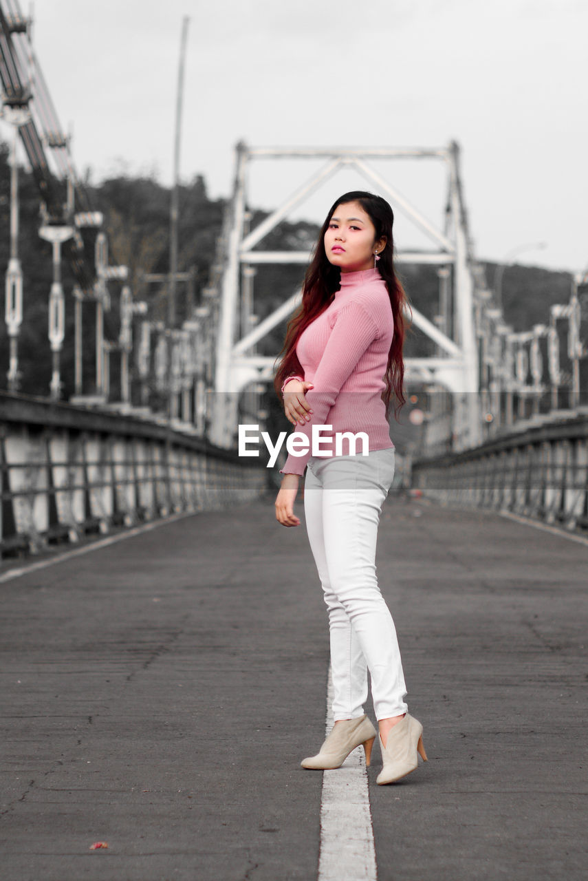 Portrait of woman standing on bridge in city