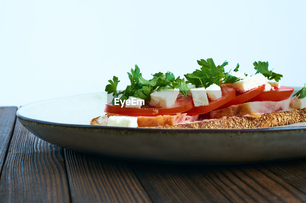 CLOSE-UP OF FRESH SALAD IN PLATE ON TABLE AGAINST WHITE BACKGROUND