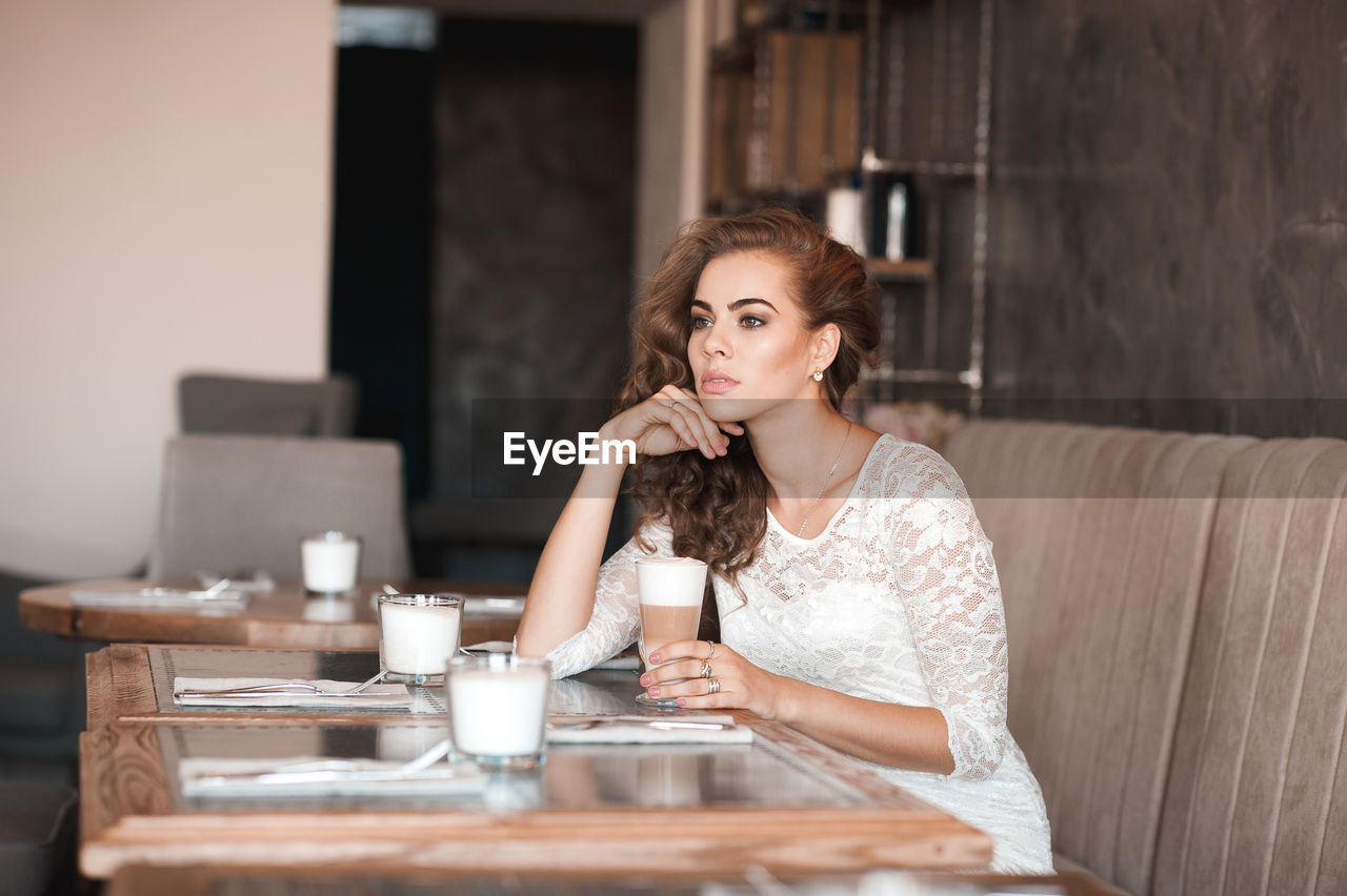 Young woman looking away while sitting at cafe