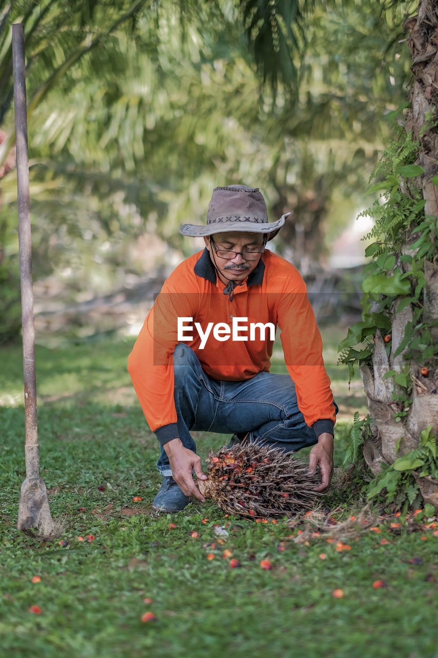 MAN WORKING ON FIELD AGAINST TREES