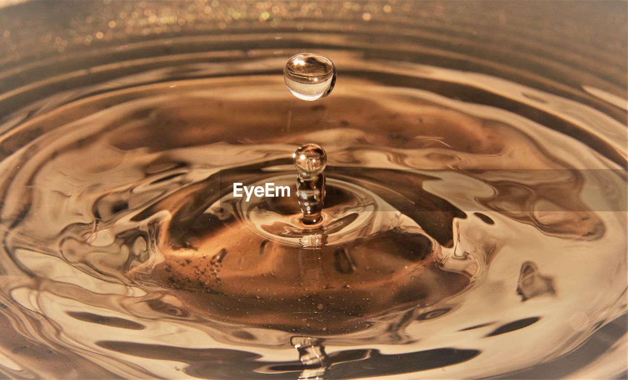 Golden water droplets splashing close up creating ripples