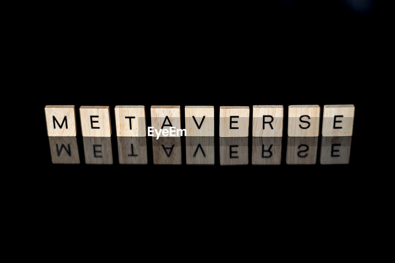 Metaverse spelled out with letter tiles on black reflective surface.