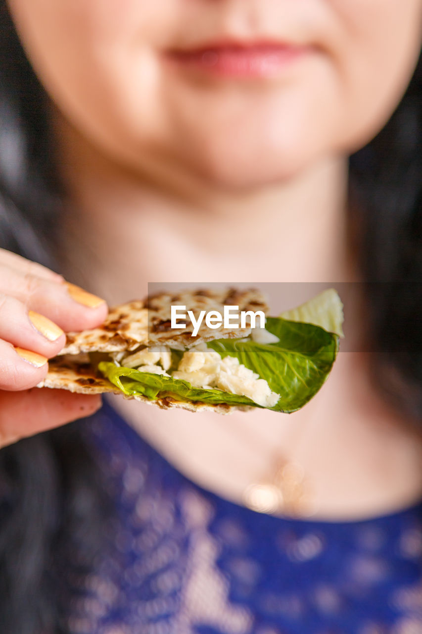 A woman without a face holds matzo and maror in her hand. vertical photo