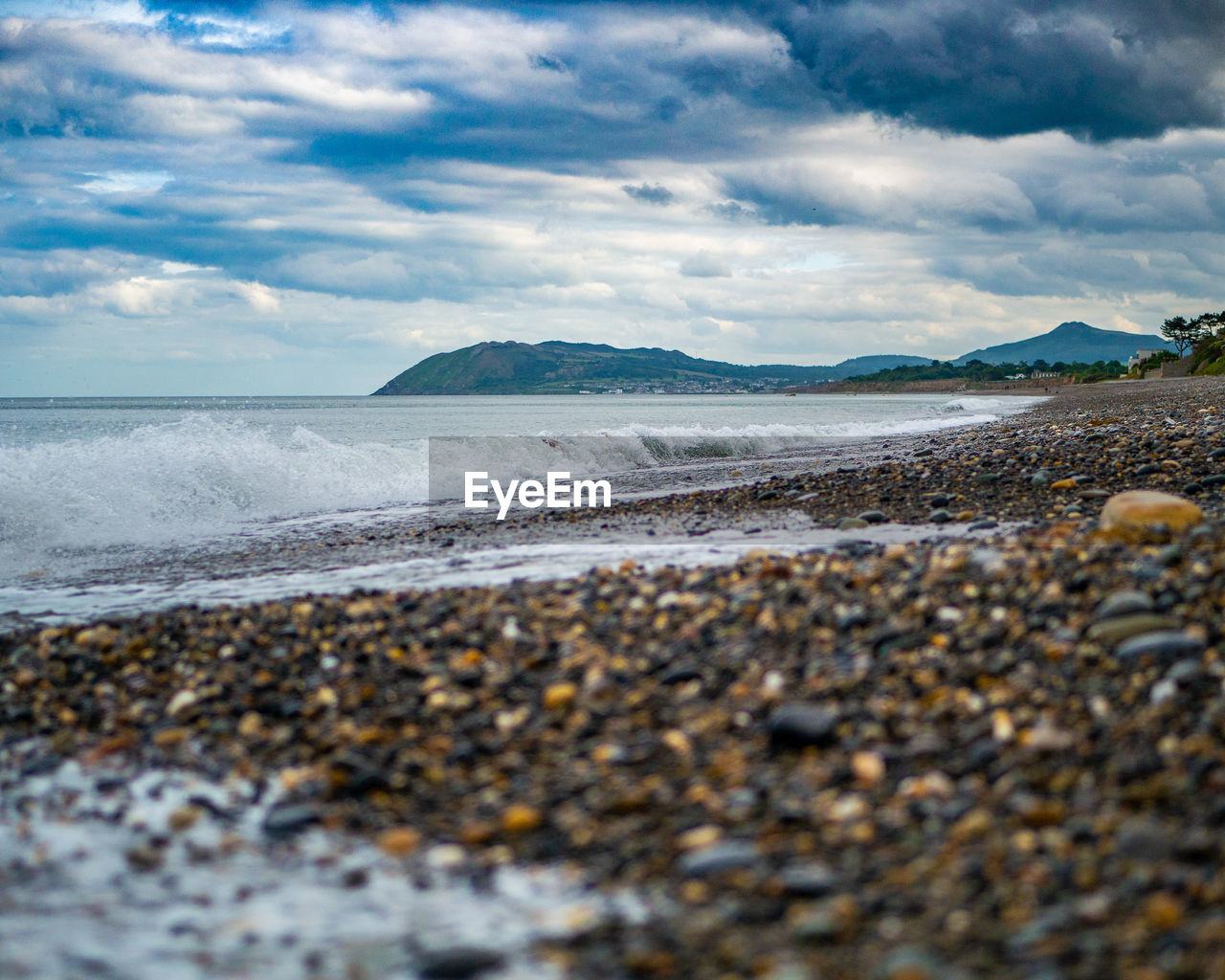 Surface level of beach against dramatic sky