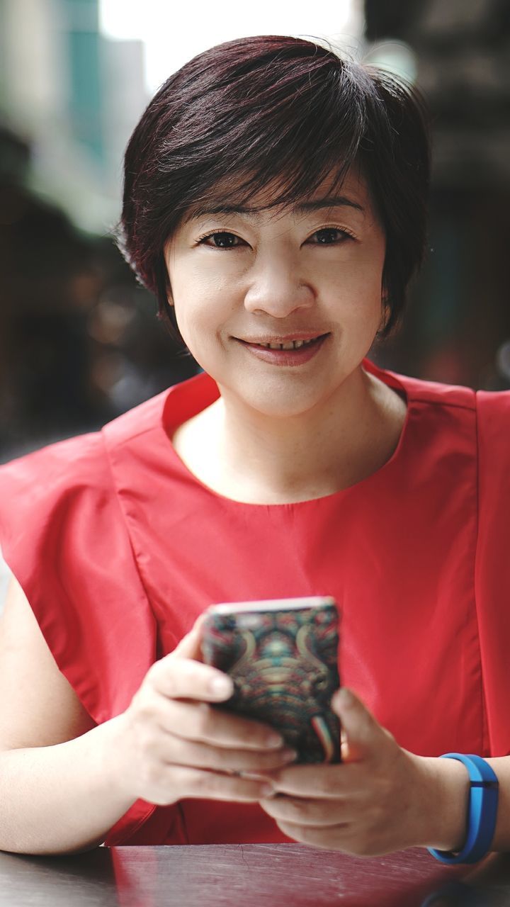 Portrait of smiling woman holding mobile phone