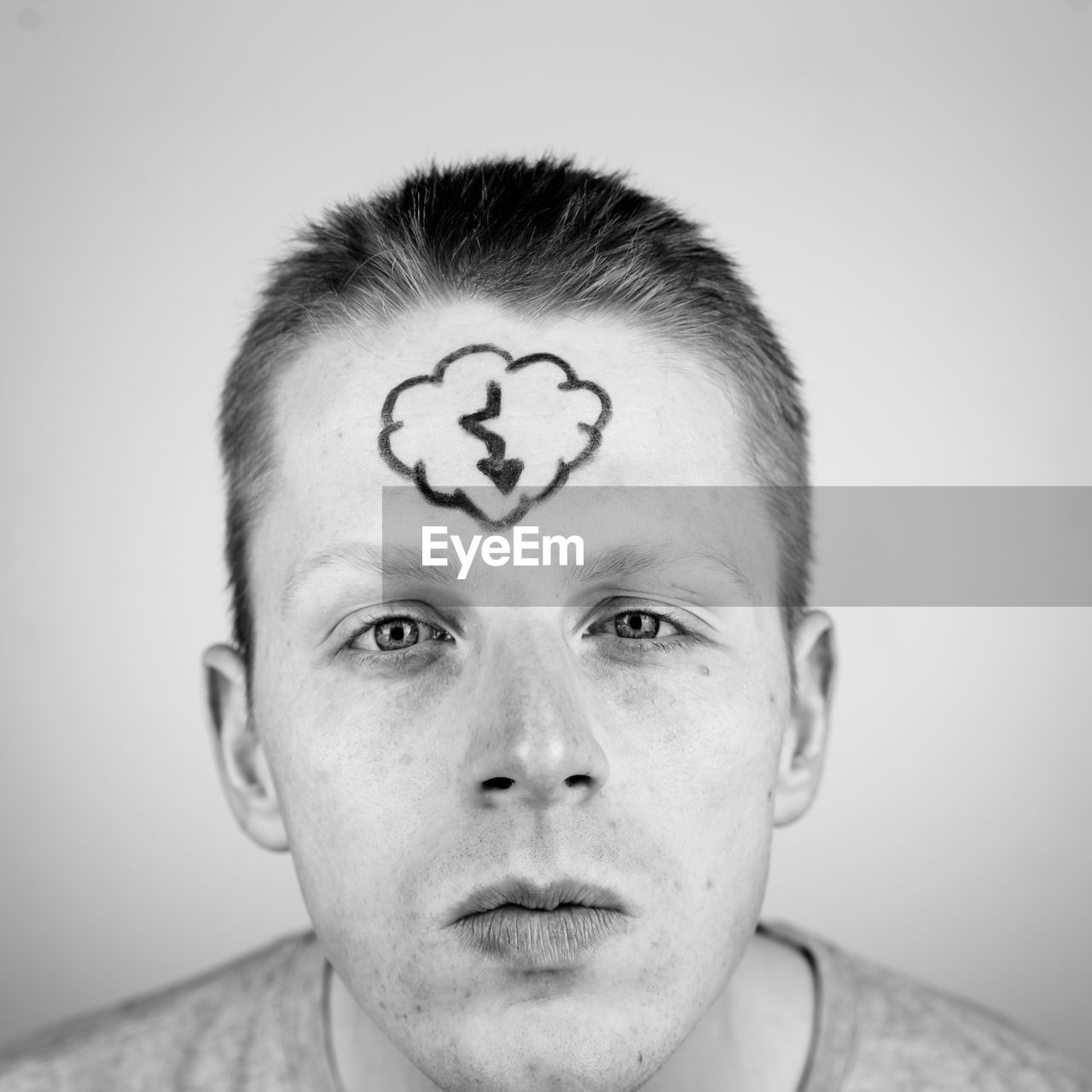 Close-up of young man with drawing on forehead against white background