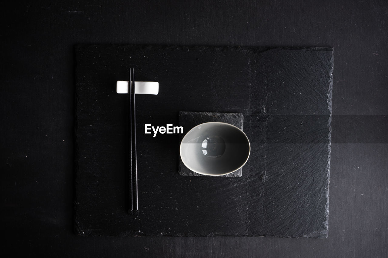 Directly above shot of bowl and chopsticks on black table