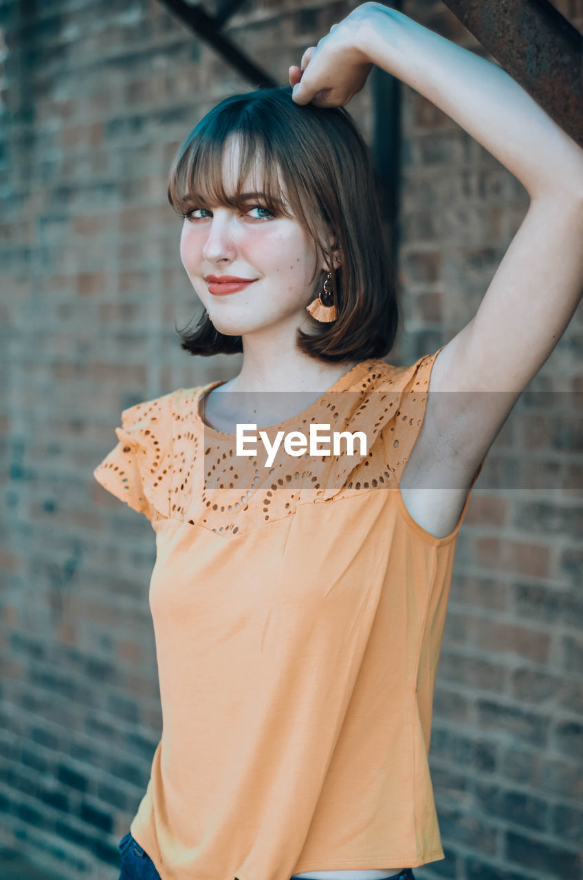 Portrait of beautiful woman standing against wall